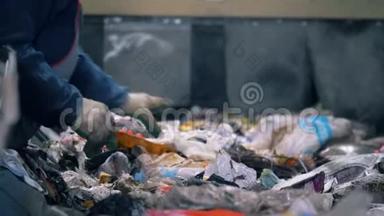工厂工人在一条线上分类垃圾，特写。工人在满是垃圾的移动线上分类纸张。